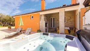 Un espace bien-être comprenant un jacuzzi, des chaises longues et une cheminée en pierre.
