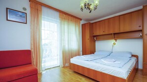 A bedroom with a wooden bed, a red sofa, and a window with curtains. - Cozy apartment in Crikvenica with WiFi (Crikvenica)