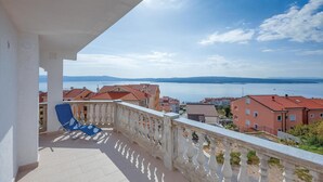 A balcony with a blue chair, overlooking a body of water and buildings. - Cozy apartment in Crikvenica with WiFi (Crikvenica)
