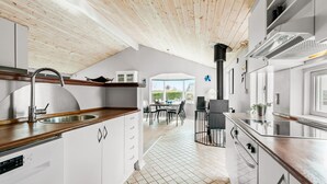 A modern kitchen with white cabinets, a wooden ceiling, and a view of the outside. - 3 bedroom nice home in Glesborg (Glesborg)
