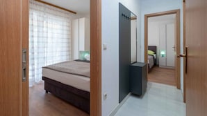 Ein Schlafzimmer mit einem Bett, einem Nachttisch, einem Spiegel und einer Tür zu einem anderen Raum.