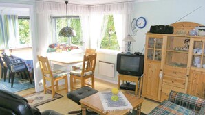 A cozy living room with a television, wooden furniture, and a dining area with a table and chairs.
