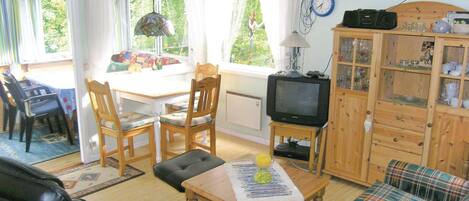 A cozy living room with a television, wooden furniture, and a dining area with a table and chairs.