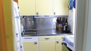A compact kitchen with a stainless steel sink, a small countertop, and yellow cabinets.