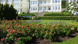 A large, multi-story building with a symmetrical facade, a central staircase, and a well-maintained garden with flowering plants. - *****Düne25 ++with SEA VIEW and only 10m from the beach++ - Apartment with 2 bedrooms (Zinnowitz)