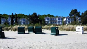 A beach with green beach chairs and a numbered trash bin. - *****Düne25 ++with SEA VIEW and only 10m from the beach++ - Apartment with 2 bedrooms (Zinnowitz)