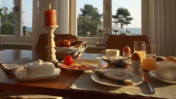 A breakfast table with croissants, eggs, and orange juice, overlooking a scenic view. - *****Düne25 ++with SEA VIEW and only 10m from the beach++ - Apartment with 2 bedrooms (Zinnowitz)