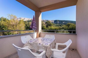 Un balcone con tavolo e sedie, vista su un paesaggio montuoso.