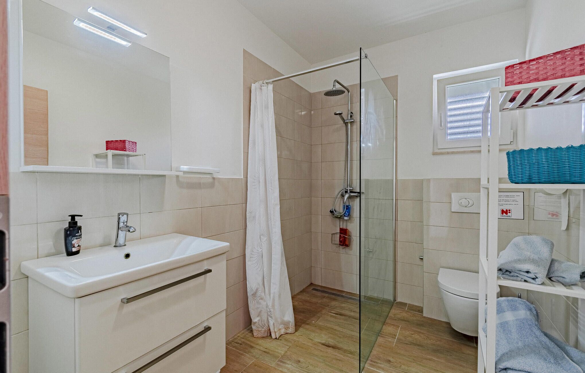 A modern bathroom with a glass shower enclosure, a white sink, and a toilet.