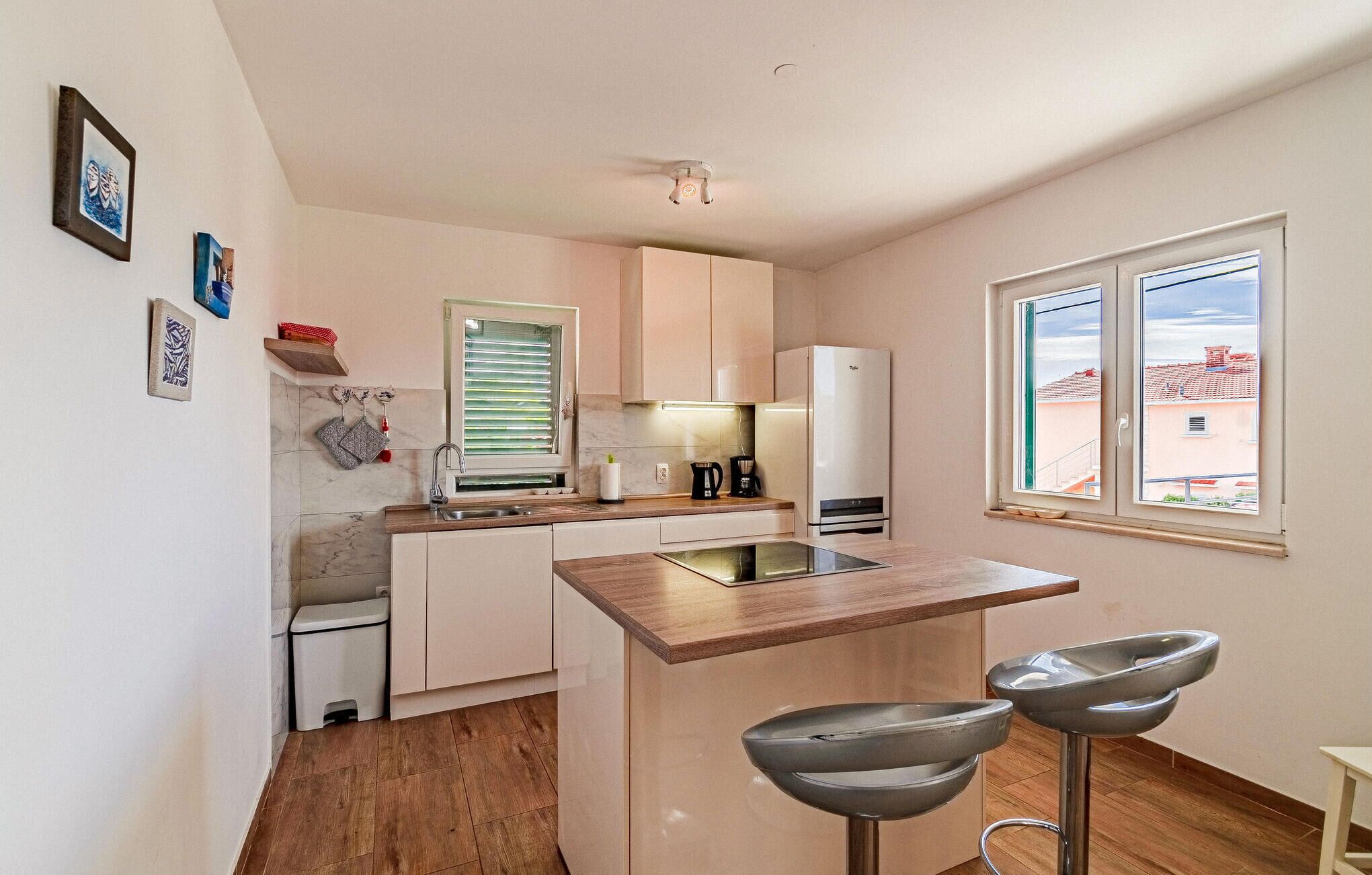 A compact kitchen with a built-in stove, a sink, and a window with a view of buildings.