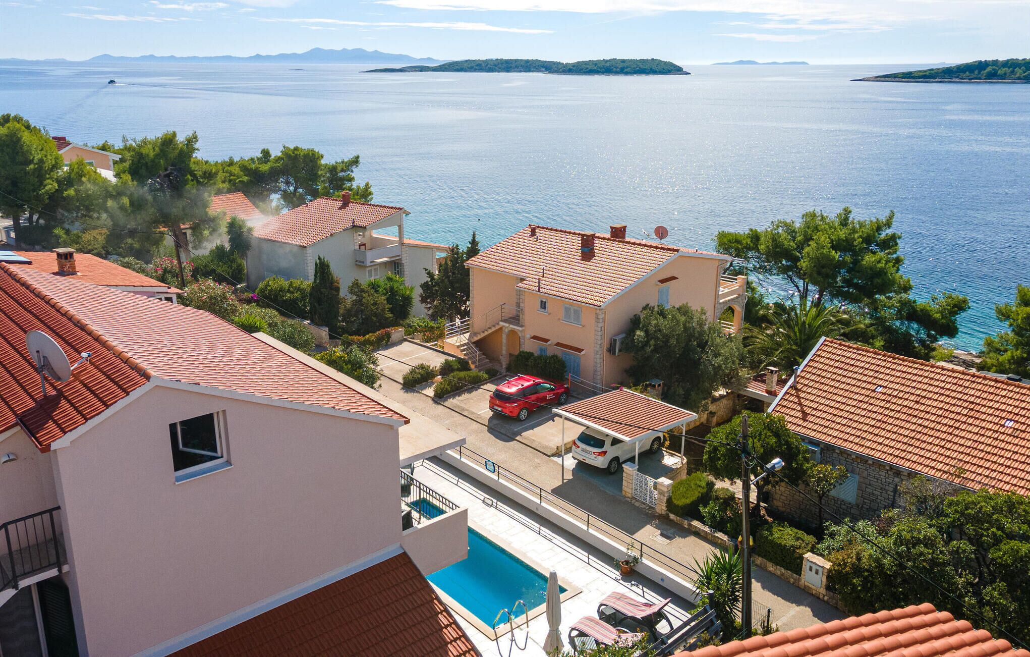 A coastal residential area with houses, a swimming pool, and a view of the sea.