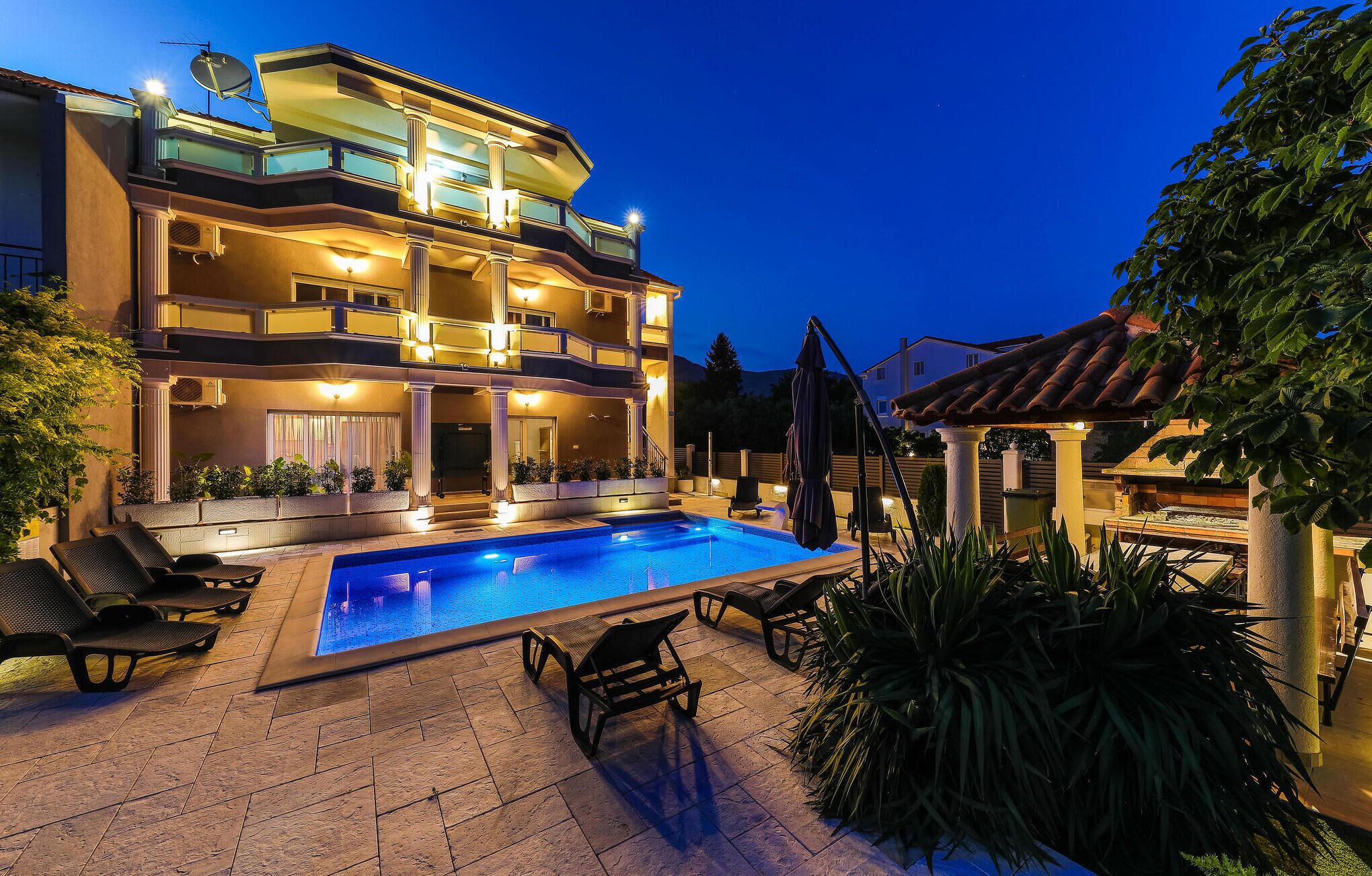 Ein mehrstöckiges Gebäude mit Pool, Sitzgelegenheiten im Freien und einer Pergola.
