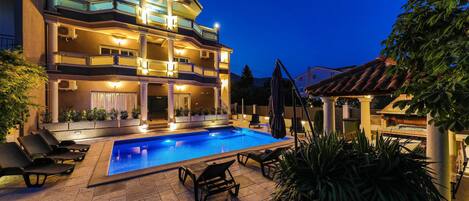 Ein mehrstöckiges Gebäude mit Pool, Sitzgelegenheiten im Freien und einer Pergola.