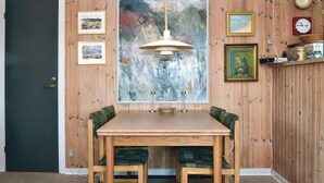 A dining area with a wooden table and chairs, a large abstract painting, and a clock on the wall. - 4 bedroom gorgeous home in Fanø (Fanø)