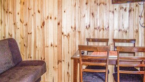 Una habitación con pared de madera, una mesa de madera con cuatro sillas y un sofá.