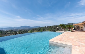 A clear blue infinity pool with a view of distant mountains and a lush landscape. - Lovely home in Sainte-Maxime with WiFi (Sainte-Maxime)
