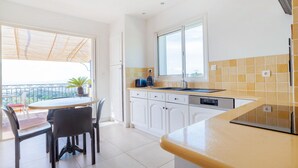 A modern kitchen with white cabinets, a built-in dishwasher, and a window overlooking a balcony. - Lovely home in Sainte-Maxime with WiFi (Sainte-Maxime)