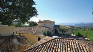 A building with a terracotta tiled roof, a courtyard with a tree, and a view of distant hills. - Lovely home in Sainte-Maxime with WiFi (Sainte-Maxime)