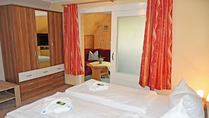 Une chambre d’hôtel comprenant un lit, une armoire, un bureau et une petite table avec une chaise.