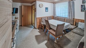 Una stanza accogliente con un tavolo da pranzo in legno, panche imbottite, un divano e una TV.