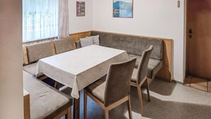 Zona pranzo con un tavolo rettangolare, sei sedie, una panca di legno e due quadri appesi al muro.