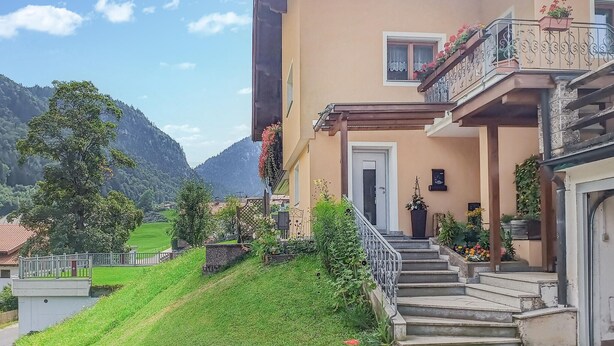 Un edificio a due piani con un balcone, una scala e vista su un paesaggio montuoso.