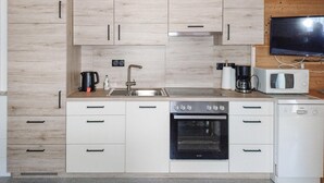 Una cucina moderna con mobili chiari in legno, un lavello in acciaio inossidabile, un forno Bosch e una lavastoviglie bianca.