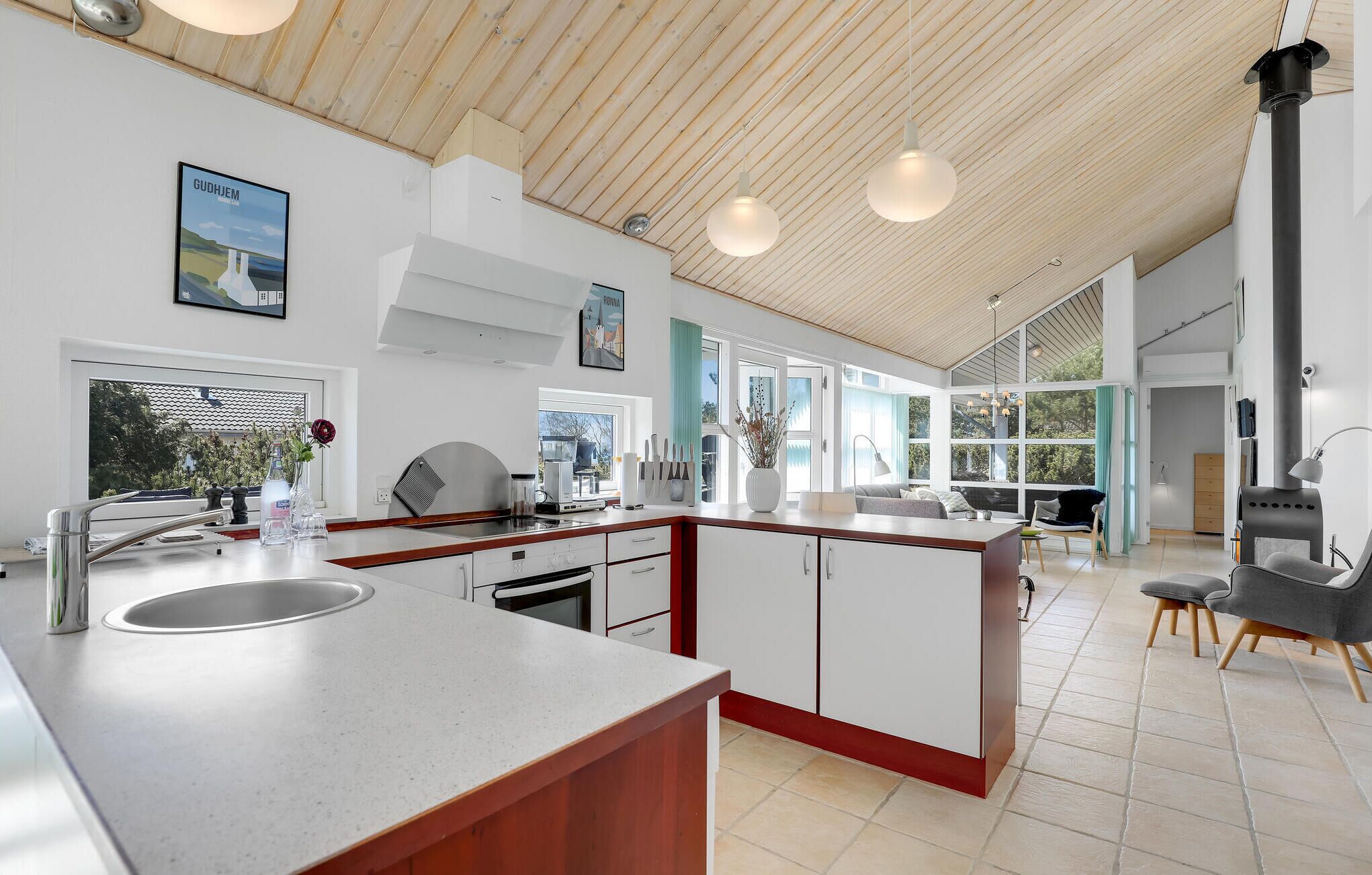 Een moderne keuken met een groot eiland, inbouwapparatuur en grote ramen met uitzicht op de omgeving.