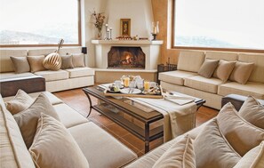 A cozy living room with a fireplace, sofas, and a coffee table set with breakfast items. - Beautiful home in Houdetsi,Heraklio (Houdetsi,Heraklio)