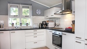 Cocina moderna con armarios blancos, extractor de acero inoxidable y ventana con vistas a zonas verdes.