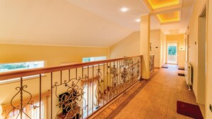 A spacious hallway with a wooden floor, a decorative railing, and a view of the outdoors through a window. - Awesome apartment in Herceg Novi (Herceg Novi)