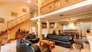 A spacious living area with a high ceiling, a wooden staircase, and a dining area with wooden furniture. - Awesome apartment in Herceg Novi (Herceg Novi)