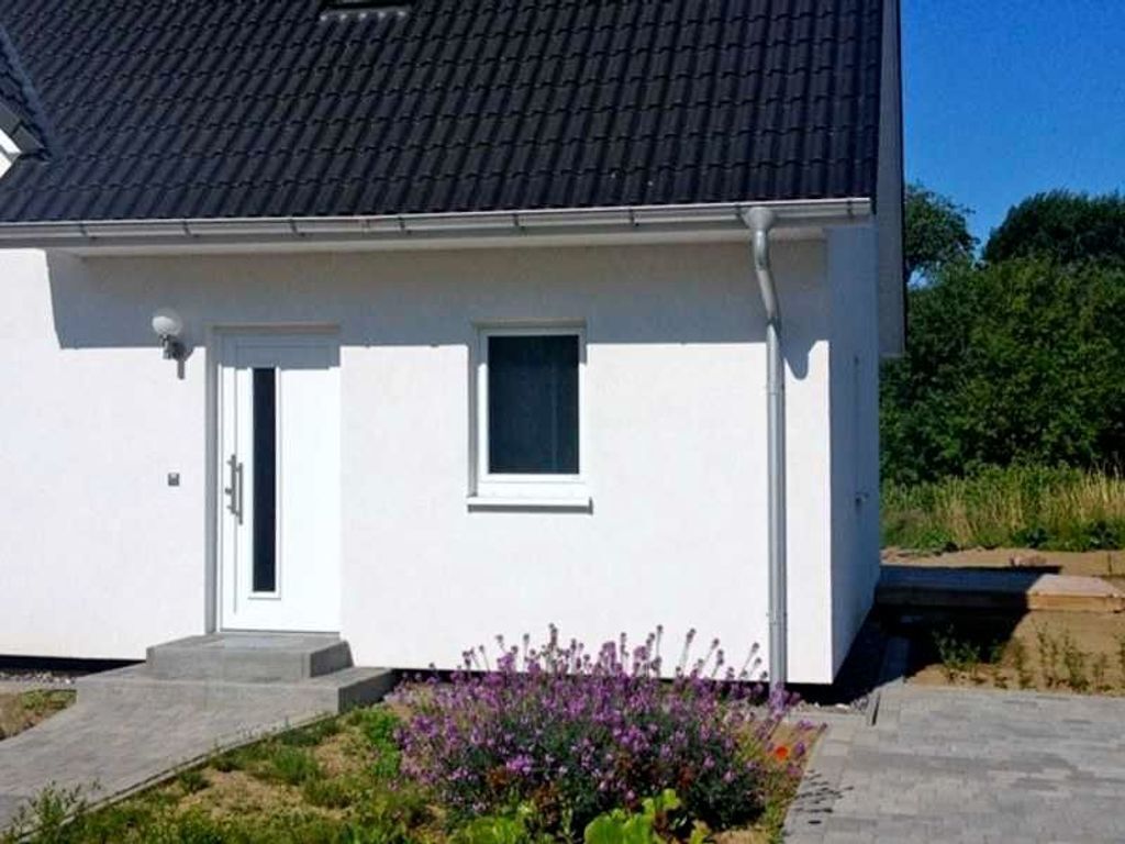 A white building with a dark roof, a small window, and a door.