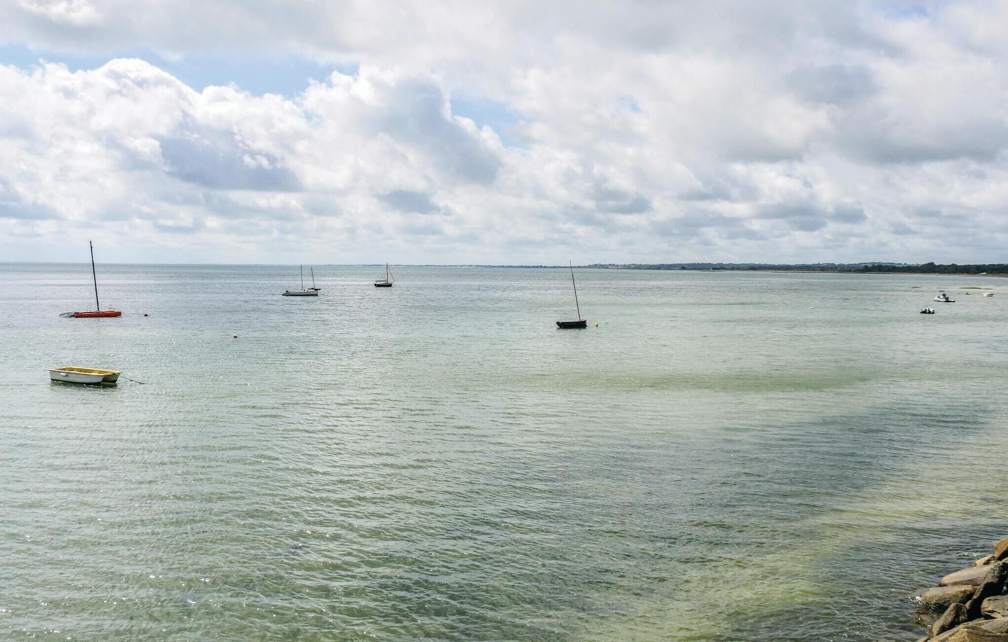 A calm sea with several boats and a buoy.