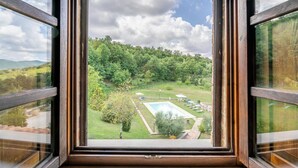 A view through a window of a pool area with a lawn, trees, and a clear sky. - Beautiful home in Città´di Castello -PG- (Città´di Castello -PG-)