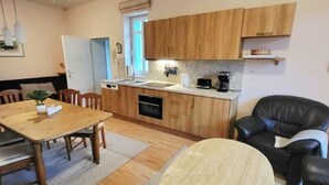 Une cuisine de taille réduite avec des meubles de rangement en bois, une table à manger et un fauteuil en cuir noir.