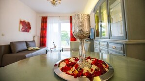 Una mesa de comedor con un centro de mesa de vidrio decorativo y un plato de pétalos de rosa.