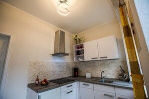 A modern kitchen with white cabinets, a stainless steel range hood, and a built-in island with a sink.