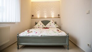 Un dormitorio con cama, ventana con persianas, radiador y pared con textura sobre la cama.