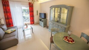 Una sala de estar con un sofá, una mesa de comedor con un plato de comida, un televisor y un mueble.