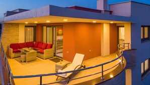 Un espace de vie extérieur moderne, avec un canapé rouge, des meubles en osier et une chaise longue.