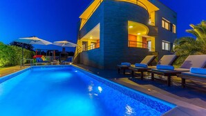 Un hôtel moderne doté d’une piscine, d’un espace extérieur aménagé et d’une terrasse bien éclairée.