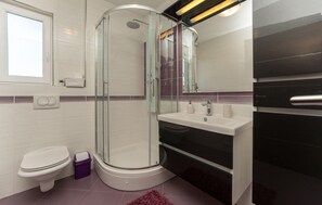 Une salle de bain moderne avec une douche à parois de verre, des toilettes et un lavabo.