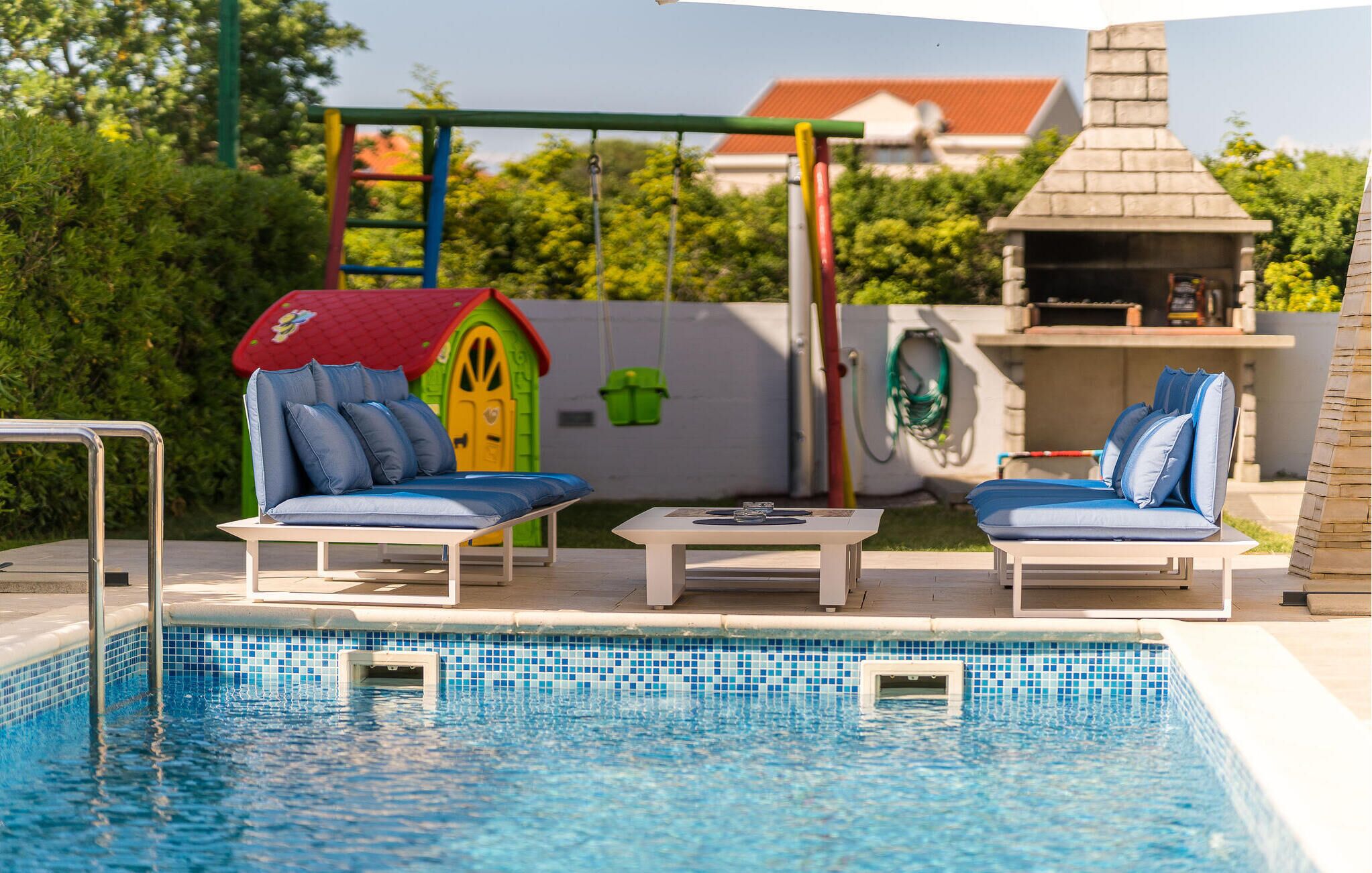 A poolside area with two lounge chairs, a children's playhouse, and a barbecue grill.
