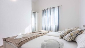 A neatly made bed with a white and beige blanket, a pair of white towels, and patterned pillows. - Holiday apartment with balcony and air conditioning (Dramalj)