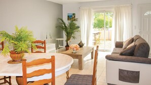 A living room with a sofa, a dining table with chairs, and a large window with curtains. - Stunning home in Lançon de Provence (Lançon de Provence)