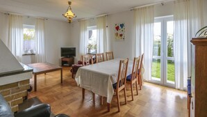 Un coin repas avec une table dressée pour quatre personnes, un téléviseur et une cheminée.