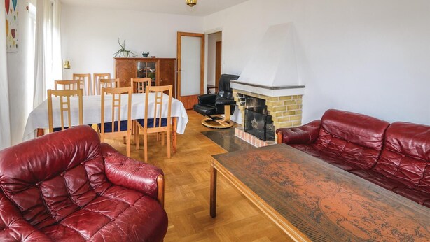Un salon avec une cheminée, des canapés en cuir, une table à manger avec des chaises et un buffet en bois.
