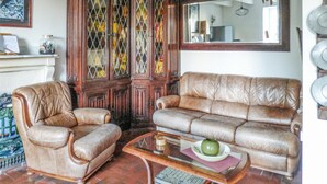 A living room with a brown leather sofa, a brown leather armchair, and a glass coffee table with a green vase. - 2 bedroom lovely home in Pleubian (Pleubian)