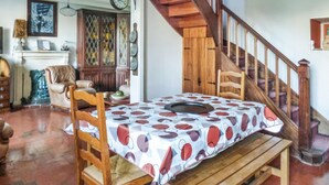 A dining area with a wooden table and benches, a staircase with wooden railings, and a fireplace with a mantel. - 2 bedroom lovely home in Pleubian (Pleubian)